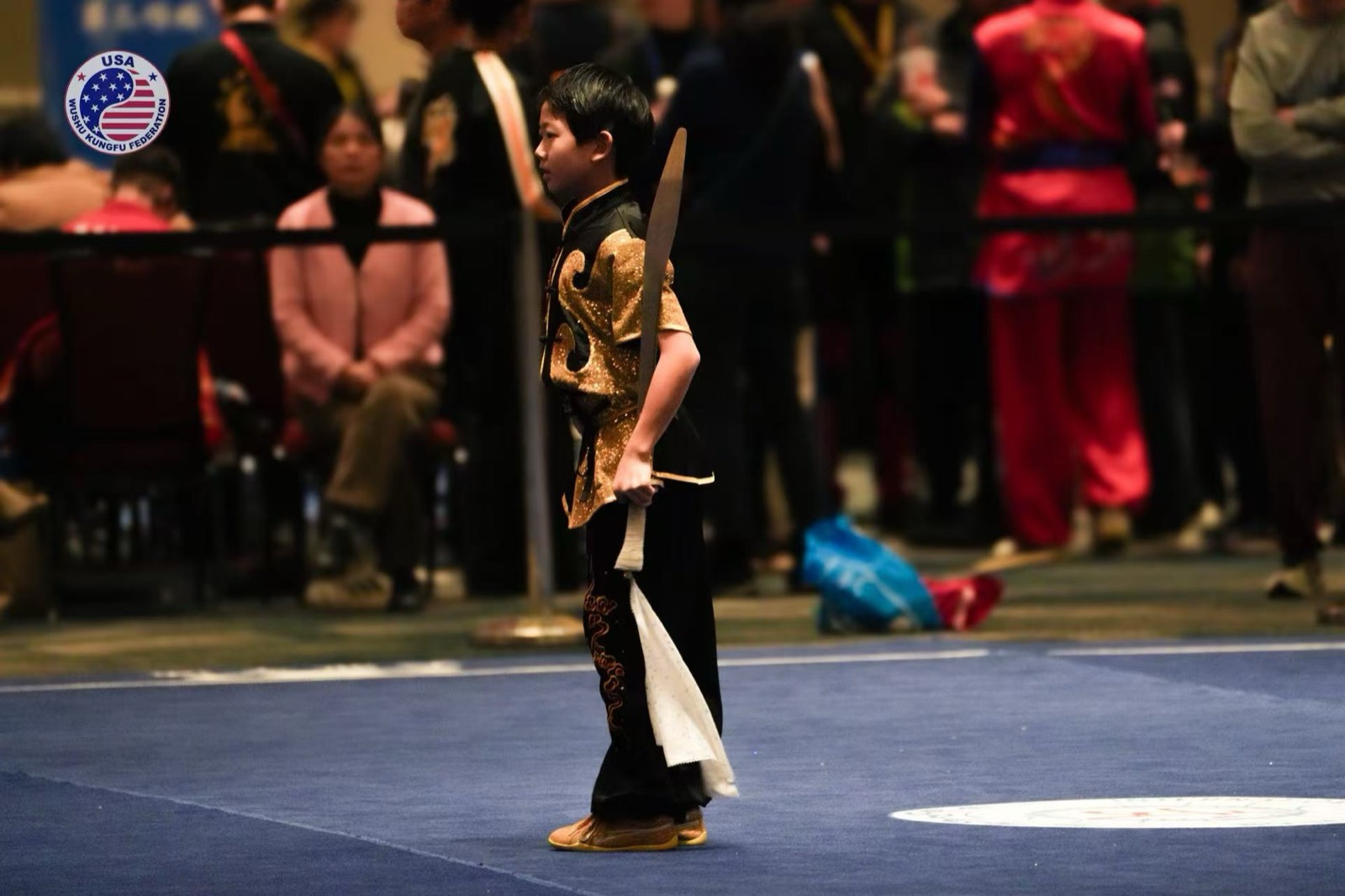 A young competitor holds a sword at the start of a routine