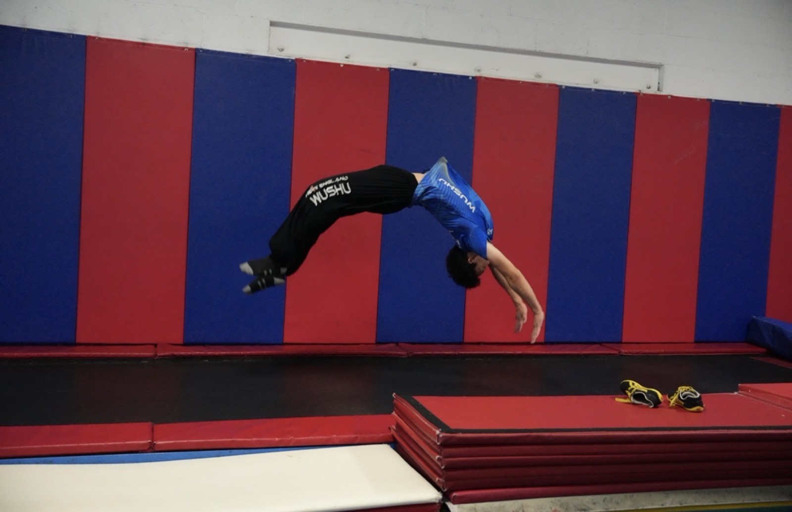 A student flips over the mats in the tumbling room